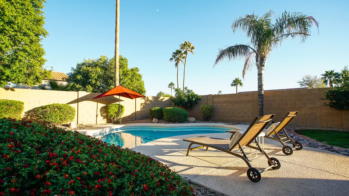 This image features a tranquil swimming pool surrounded by elegant lounge chairs, swaying palm trees, and lush landscape plants. The inviting water and resort-style seating evoke a sense of luxury and leisure, while the backdrop of palm trees hints at a quintessential Scottsdale lifestyle.