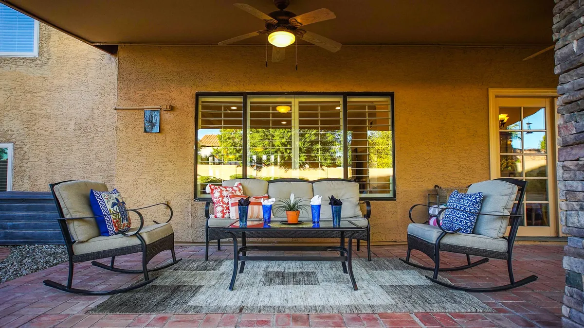 A stylish outdoor seating area with comfortable chairs, colorful pillows, decorative plants, and a sleek coffee table. The space feels welcoming and is surrounded by natural elements, offering a perfect spot for socializing or unwinding after a day out.