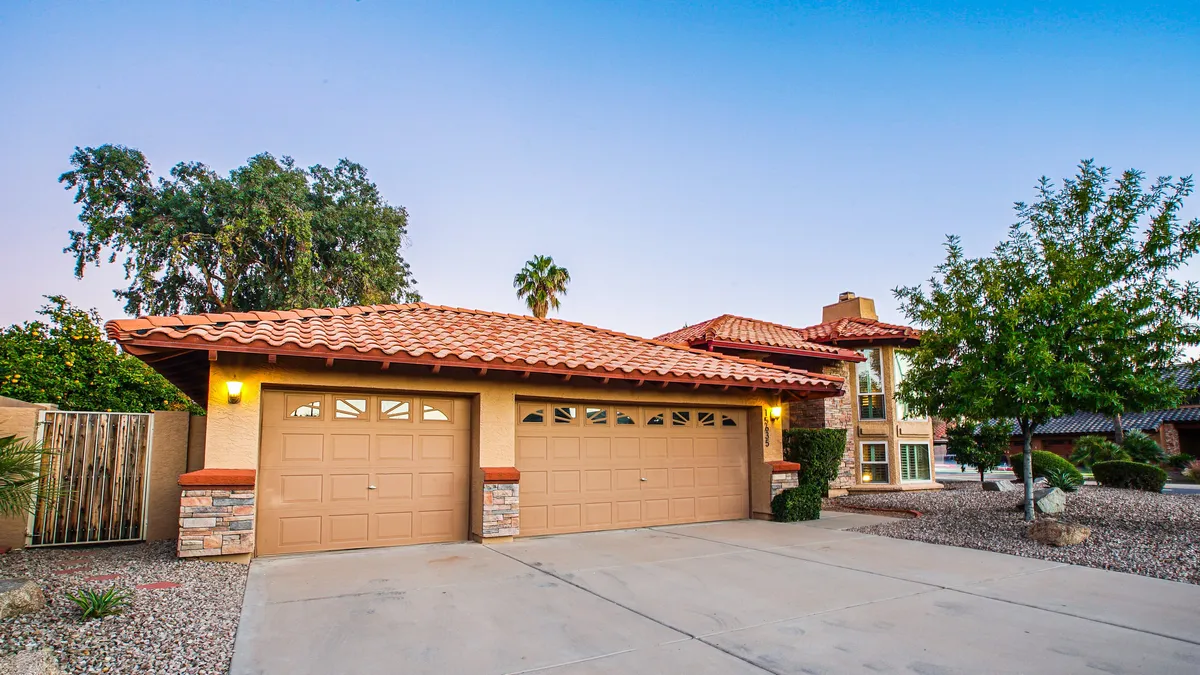 An exterior view of the home’s garages, surrounded by attractive landscaping and an inviting entryway. The scene is bathed in soft natural light, conveying a sense of welcome and convenience.